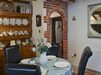 a dining room with a table with a vase of flowers at Tattlepot Farmhouse in Tivetshall Saint Margaret