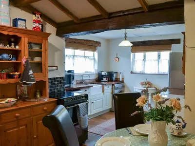 a kitchen with white cabinets and a table with flowers at Tattlepot Farmhouse in Tivetshall Saint Margaret