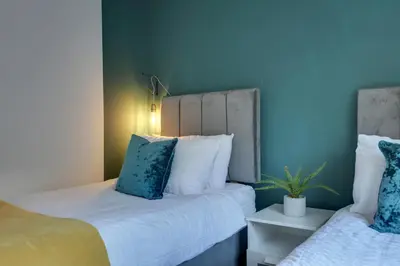 a bedroom with two beds with blue walls and a plant at George Suite - Central Location - Free Allocated Parking in Chelmsford