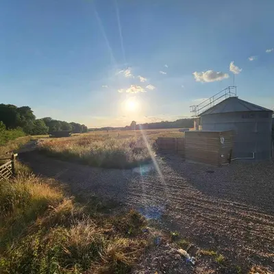 a building in a field with the sun in the sky at The Stables & Silos in Braintree