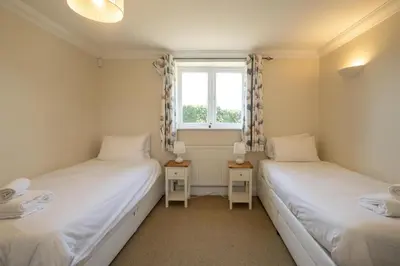 two twin beds in a room with a window at 2 Hazelwood - 2 bedroom house near Aldeburgh & Snape Maltings - Aldeburgh Coastal Cottages in Aldringham