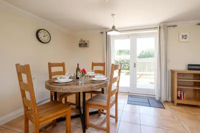 a dining room with a table and chairs and a clock at 2 Hazelwood - 2 bedroom house near Aldeburgh & Snape Maltings - Aldeburgh Coastal Cottages in Aldringham