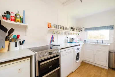 a white kitchen with a stove and a sink at Shore Cote, Thorpeness in Thorpeness