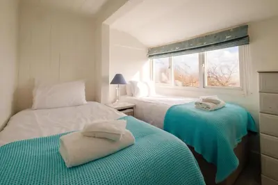 a white bedroom with two beds and a window at Shore Cote, Thorpeness in Thorpeness