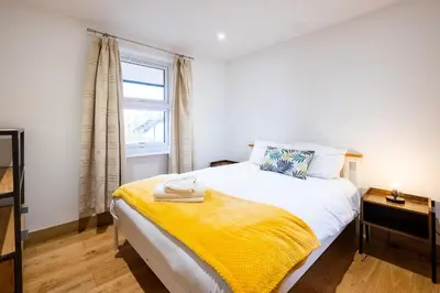 a bedroom with a bed with a yellow blanket on it at Three Tuns Apartments - Sycamore in Pettistree