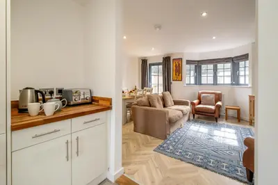 a kitchen and living room with a couch and a table at 5 Oakes Court in Thorpeness
