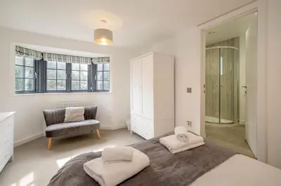 a bedroom with a large bed and a chair at 5 Oakes Court in Thorpeness