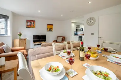 a dining room and living room with a table and wine glasses at 5 Oakes Court in Thorpeness