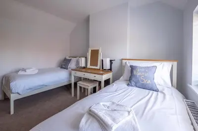 a bedroom with two beds and a desk with a mirror at Pigwig Cottage, Thorpeness in Thorpeness