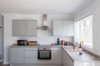a kitchen with white cabinets and a stove top oven at Pigwig Cottage, Thorpeness in Thorpeness