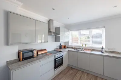 a kitchen with white cabinets and stainless steel appliances at Pigwig Cottage, Thorpeness in Thorpeness
