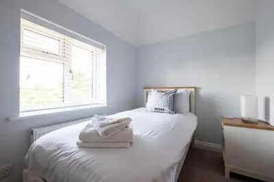 a white bedroom with a bed with towels on it at Pigwig Cottage, Thorpeness in Thorpeness