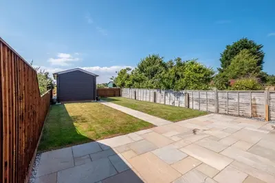 a garden with a fence and a patio at Pigwig Cottage, Thorpeness in Thorpeness