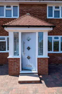 a white door with a red roof on a brick house at Pigwig Cottage, Thorpeness in Thorpeness
