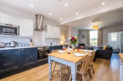a kitchen and living room with a table and chairs at Elm Cottage in Aldeburgh
