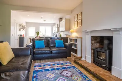 a living room with a leather couch and a fireplace at Elm Cottage in Aldeburgh