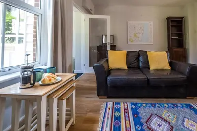 a living room with a black couch and a table at Elm Cottage in Aldeburgh