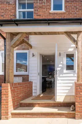 a house with a white door and a brick building at Elm Cottage in Aldeburgh