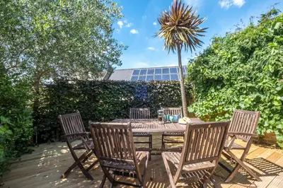 a patio with a table and chairs and a palm tree at Elm Cottage in Aldeburgh