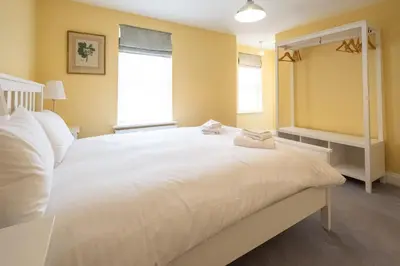 a large white bed in a room with yellow walls at 4 Wards Place in Aldeburgh
