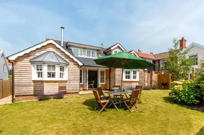 a table with an umbrella in the yard of a house at The Pink House, Thorpeness in Thorpeness