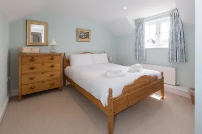 a bedroom with a bed and a dresser and a window at The Pink House, Thorpeness in Thorpeness