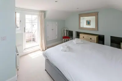 a bedroom with a large white bed and a window at The Pink House, Thorpeness in Thorpeness