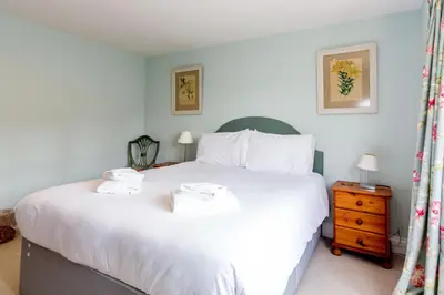 a bedroom with a large white bed with towels on it at The Pink House, Thorpeness in Thorpeness