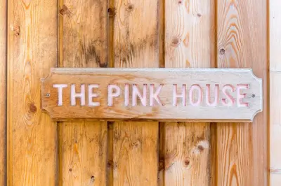 a sign that reads the pink house on a wooden door at The Pink House, Thorpeness in Thorpeness