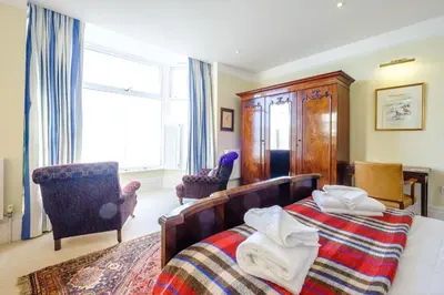 a bedroom with a bed and two chairs and a window at Gunfleet, Aldeburgh - A Large Seafront House with Stunning Sea Views from all the floors, Sleeps 14 - Aldeburgh Coastal Cottages in Aldeburgh