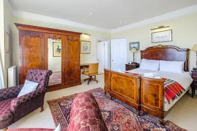 a bedroom with a large wooden bed and a couch at Gunfleet, Aldeburgh - A Large Seafront House with Stunning Sea Views from all the floors, Sleeps 14 - Aldeburgh Coastal Cottages in Aldeburgh