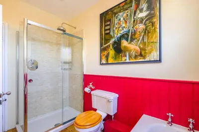 a bathroom with red walls and a painting on the wall at Gunfleet, Aldeburgh - A Large Seafront House with Stunning Sea Views from all the floors, Sleeps 14 - Aldeburgh Coastal Cottages in Aldeburgh