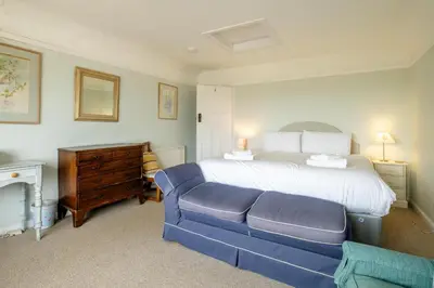 a bedroom with a bed and a blue couch at Sea View, Thorpeness in Thorpeness