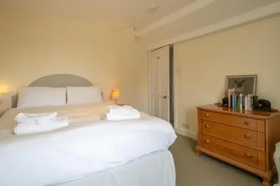 a bedroom with a large white bed and a wooden dresser at Sea View, Thorpeness in Thorpeness