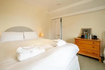 a bedroom with a white bed and a wooden dresser at Sea View, Thorpeness in Thorpeness