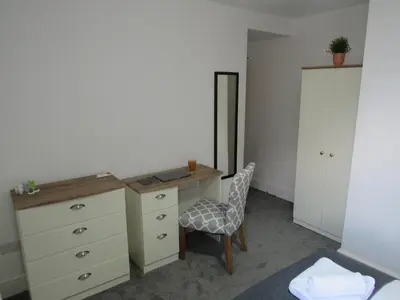 a bedroom with a dresser and a desk with a chair at The Tas Suites - Tas Accommodations in Cambridge