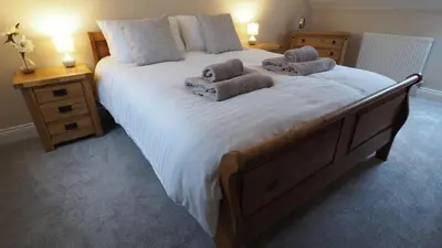 a bedroom with a large bed with towels on it at Woodlands View in Halesworth