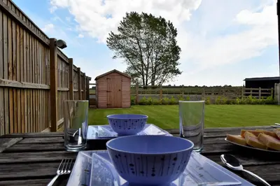 a table with bowls and glasses on a wooden deck at Woodlands View in Halesworth
