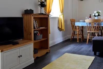 a living room with a television and a table at Woodlands View in Halesworth
