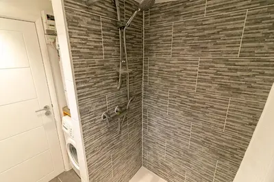 a bathroom with a shower with a brick wall at Denby Lodge in Letchworth