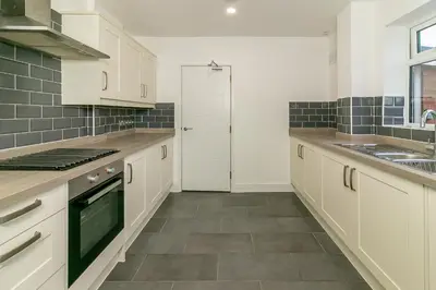a kitchen with white cabinets and a tile floor at Denby Lodge in Letchworth