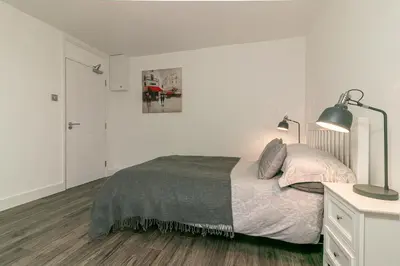a white bedroom with a bed and a lamp at Denby Lodge in Letchworth