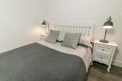a bedroom with a bed with two lamps and a nightstand at Denby Lodge in Letchworth