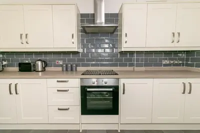 a kitchen with white cabinets and a stove at Denby Lodge in Letchworth