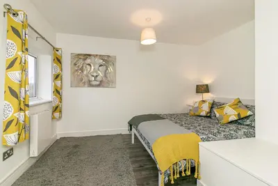 a bedroom with a bed with yellow and grey pillows at Denby Lodge in Letchworth