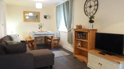 a living room with a television and a table at Hideaway Cottage in Halesworth