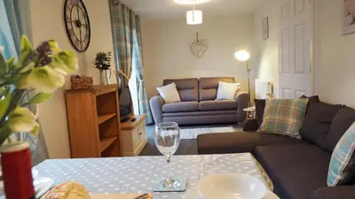 a living room with a couch and a table with a wine glass at Hideaway Cottage in Halesworth