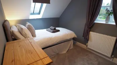 a small bedroom with a bed and a window at Hideaway Cottage in Halesworth