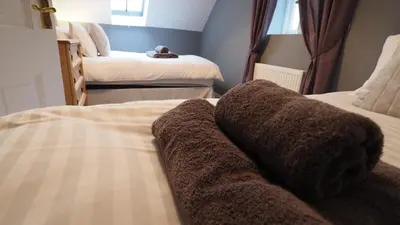 a bedroom with two beds with a blanket at Hideaway Cottage in Halesworth