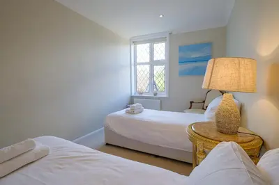 a bedroom with two beds and a lamp on a table at Turret House, Thorpeness - Close to the beach, Thorpeness Lake , Thorpeness Hotel, Golf and Country Club - Aldeburgh Coastal Cottages in Thorpeness